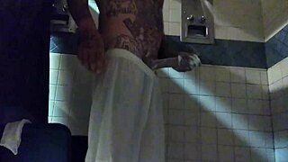 This is a webcam video of a man masturbating with a tattooed penis in the shower and ejaculating